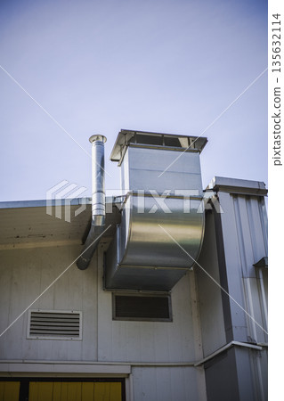 Chimney and ventilation system are attached to the exterior of a building under a clear blue sky during daytime Chimney and ventilation system are attached to the exterior of a building under a clear blue sky during daytime 135632114