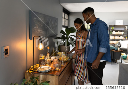 Couple preparing snacks and drinks at home for evening celebration Couple preparing snacks and drinks at home for evening celebration 135632318