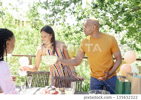Celebrating birthday outdoors, friends sharing snacks in festive atmosphere Celebrating birthday outdoors, friends sharing snacks in festive atmosphere 135632322