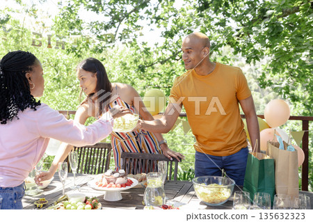Outdoor birthday party, friends sharing snacks and laughter under sunny trees Outdoor birthday party, friends sharing snacks and laughter under sunny trees 135632323
