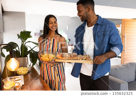 Preparing snacks for celebration, African American couple smiling at home kitchen Preparing snacks for celebration, African American couple smiling at home kitchen 135632325