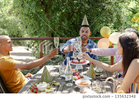 Toasting with champagne, friends celebrating birthday at outdoor party with joy Toasting with champagne, friends celebrating birthday at outdoor party with joy 135632348