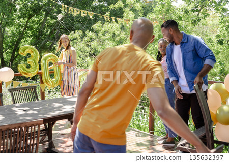 Preparing outdoor birthday, friends decorating garden with balloons and festive items Preparing outdoor birthday, friends decorating garden with balloons and festive items 135632397