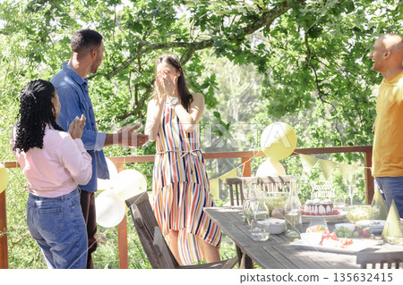 Celebrating surprise party outdoors, friends with balloons and decorations having fun 135632415