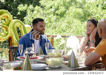 Celebrating outdoors, friends enjoying birthday party with food and decorations Celebrating outdoors, friends enjoying birthday party with food and decorations 135632417