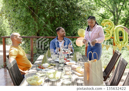 Celebrating outdoors, friends enjoying birthday party with food and decorations Celebrating outdoors, friends enjoying birthday party with food and decorations 135632422