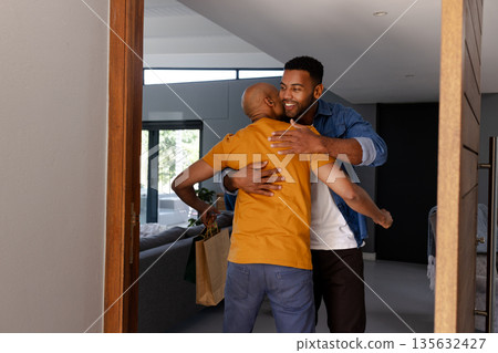 African American men embracing warmly at home, celebrating joyful reunion African American men embracing warmly at home, celebrating joyful reunion 135632427