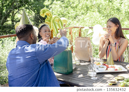 Celebrating birthday outdoors, friends exchanging gifts with festive decorations around 135632432