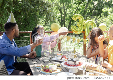 Celebrating birthday outdoors, friends sharing champagne and cake in festive atmosphere Celebrating birthday outdoors, friends sharing champagne and cake in festive atmosphere 135632445