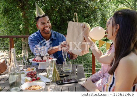 Exchanging gifts, friends celebrating birthday outdoors with festive treats together 135632469
