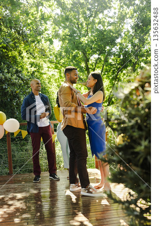 Dancing outdoors, African American couple at party with friends and balloons Dancing outdoors, African American couple at party with friends and balloons 135632488