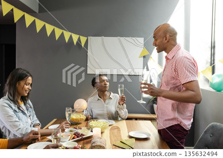 Celebrating at home, African American friends raising glasses and having conversation Celebrating at home, African American friends raising glasses and having conversation 135632494