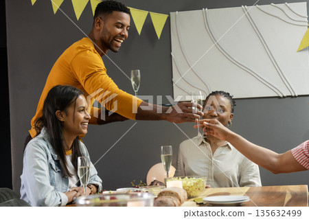 Friends celebrating at home, toasting with champagne and enjoying festive gathering Friends celebrating at home, toasting with champagne and enjoying festive gathering 135632499
