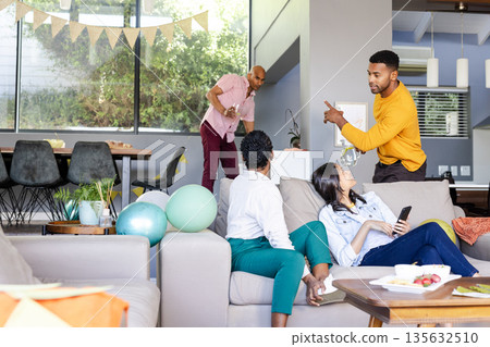 Friends relaxing on sofa at home, chatting and enjoying casual gathering 135632510