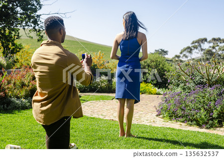 Man proposing to woman in garden, capturing romantic moment on sunny day Man proposing to woman in garden, capturing romantic moment on sunny day 135632537