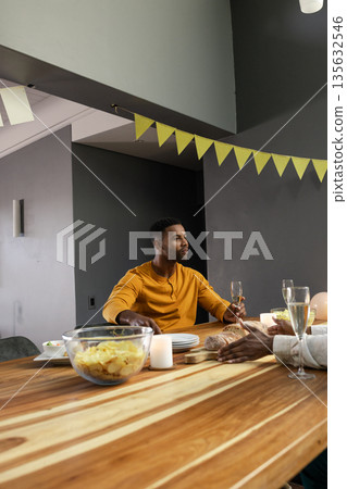 Man in yellow shirt enjoying dinner with friends, holding champagne glass Man in yellow shirt enjoying dinner with friends, holding champagne glass 135632546