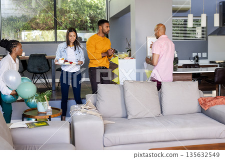 Friends gathering at home, enjoying food and conversation in modern living room Friends gathering at home, enjoying food and conversation in modern living room 135632549