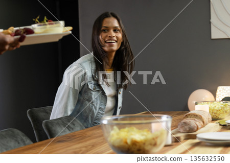 Smiling woman enjoying dinner party with friends, seated at dining table Smiling woman enjoying dinner party with friends, seated at dining table 135632550