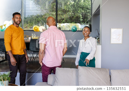 Friends chatting and laughing at home during casual celebration gathering Friends chatting and laughing at home during casual celebration gathering 135632551