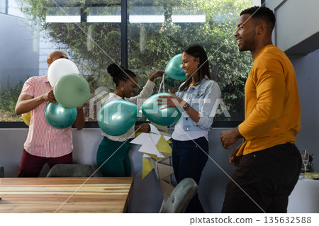 Friends decorating with balloons and laughing together at home celebration Friends decorating with balloons and laughing together at home celebration 135632588