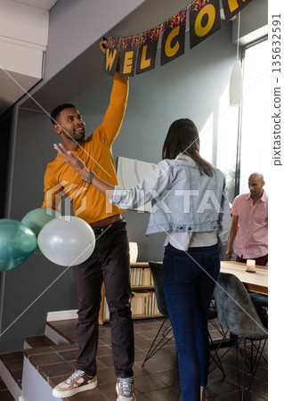 Friends decorating home with balloons and welcome banner for celebration Friends decorating home with balloons and welcome banner for celebration 135632591