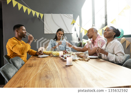 Friends enjoying dinner party, toasting with champagne around festive table setting Friends enjoying dinner party, toasting with champagne around festive table setting 135632592