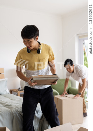 Father and son unpacking boxes in bedroom, enjoying new home together Father and son unpacking boxes in bedroom, enjoying new home together 135632651