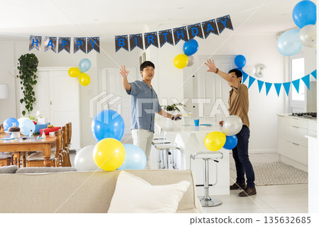 Decorating living room with balloons, friends preparing for birthday celebration, smiling Decorating living room with balloons, friends preparing for birthday celebration, smiling 135632685