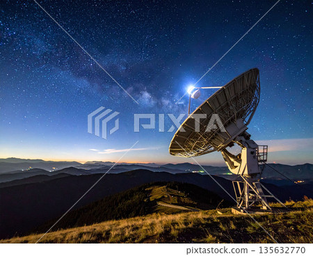 A large radio telescope searches the starry night sky atop a mountain ridge. This dramatic scene represents scientific discovery, data transmission, and the vast beauty of our cosmos. 135632770