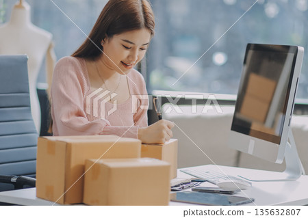 Starting small businesses SME owners female entrepreneurs check online orders to prepare to pack the boxes, sell to customers, sme business ideas online. Starting small businesses SME owners female entrepreneurs check online orders to prepare to pack the boxes, sell to customers, sme business ideas online. 135632807