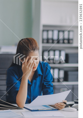 Young businesswoman is holding two credit cards with a worried expression, trying to decide which one to use to pay off her debt Young businesswoman is holding two credit cards with a worried expression, trying to decide which one to use to pay off her debt 135632891