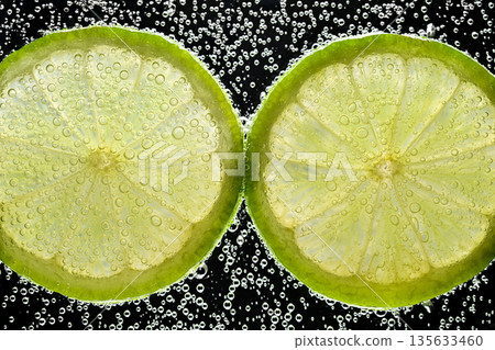 Two slices of lime with bubbles in the middle Two slices of lime with bubbles in the middle 135633460