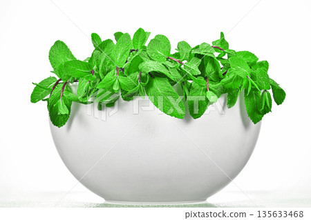 A white bowl filled with green mint leaves A white bowl filled with green mint leaves 135633468