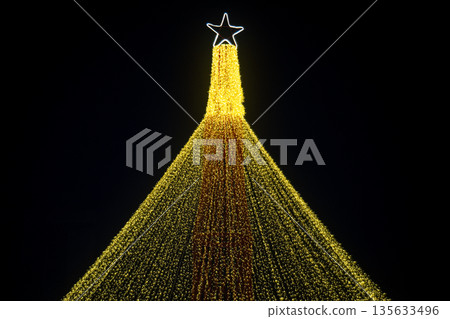 A Christmas tree with a star on top and a yellow ribbon A Christmas tree with a star on top and a yellow ribbon 135633496