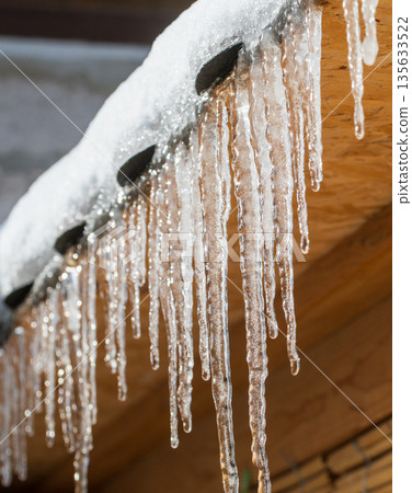 Icicles hanging from a roof, they are clear and shiny Icicles hanging from a roof, they are clear and shiny 135633522