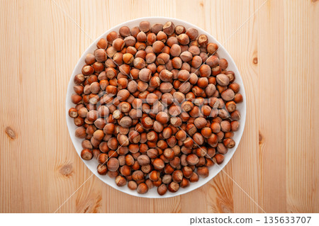 A plate of nuts is on a wooden table A plate of nuts is on a wooden table 135633707