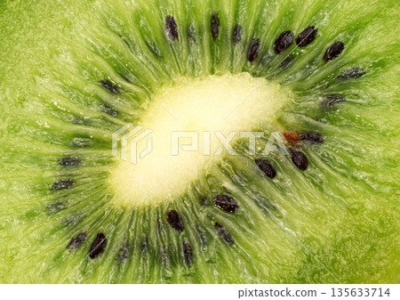 A close up of a kiwi fruit with black seeds 135633714