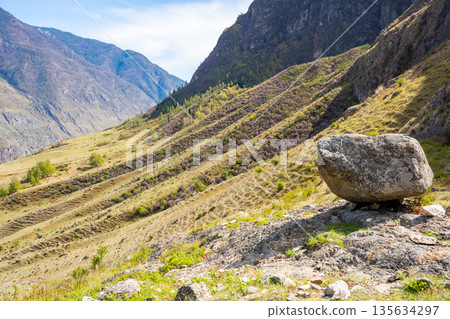 Black stone boulder on mountain with view of Chulyshman valley Altai Russia Sacred natural landmark and spiritual site 135634297