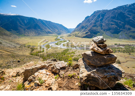 Stone cairn on mountain with view of Chulyshman valley and river in Altai Russia Symbol of hiking and nature exploration Stone cairn on mountain with view of Chulyshman valley and river in Altai Russia Symbol of hiking and nature exploration 135634309