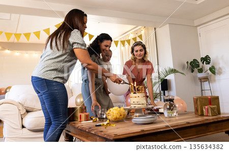 Family celebrating birthday at home, cutting cake with joyful smiles and decorations Family celebrating birthday at home, cutting cake with joyful smiles and decorations 135634382