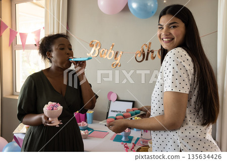Celebrating baby shower, women enjoying desserts and decorations with joyful smiles Celebrating baby shower, women enjoying desserts and decorations with joyful smiles 135634426