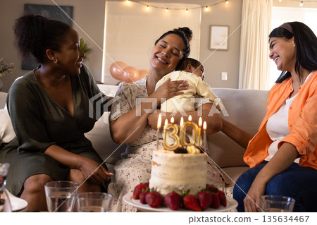 Celebrating birthday, diverse women with baby sharing cake and conversation 135634467
