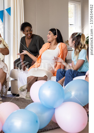 Friends enjoying lively conversation at home surrounded by colorful balloons Friends enjoying lively conversation at home surrounded by colorful balloons 135634482