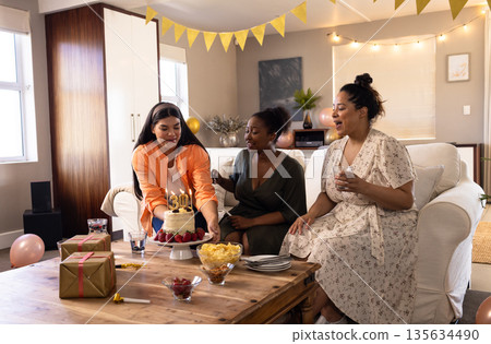 Celebrating birthday, diverse women enjoying cake and drinks in cozy living room Celebrating birthday, diverse women enjoying cake and drinks in cozy living room 135634490
