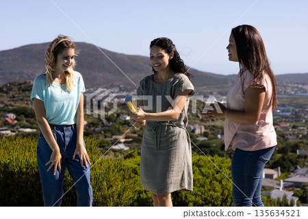 Women celebrating outdoors with party popper, enjoying joyful moment together 135634521