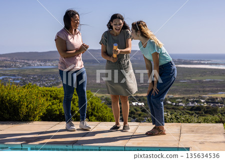 Friends celebrating by poolside with confetti popper, enjoying outdoor gathering Friends celebrating by poolside with confetti popper, enjoying outdoor gathering 135634536