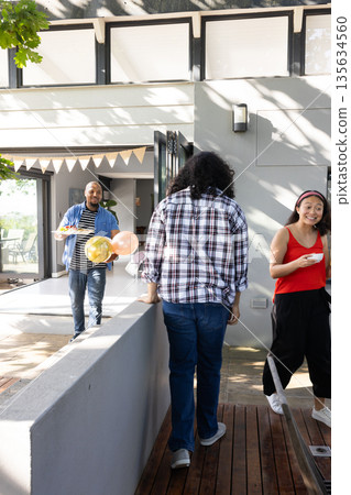 Holding balloons, friends celebrating outdoors during sunny gathering in park Holding balloons, friends celebrating outdoors during sunny gathering in park 135634560