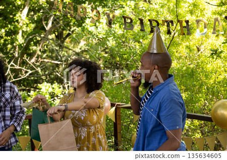 Celebrating birthday outdoors, friends wearing party hats with festive decorations Celebrating birthday outdoors, friends wearing party hats with festive decorations 135634605