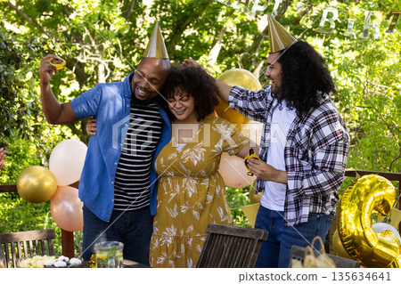 Celebrating birthday outdoors, friends wearing party hats and smiling together Celebrating birthday outdoors, friends wearing party hats and smiling together 135634641