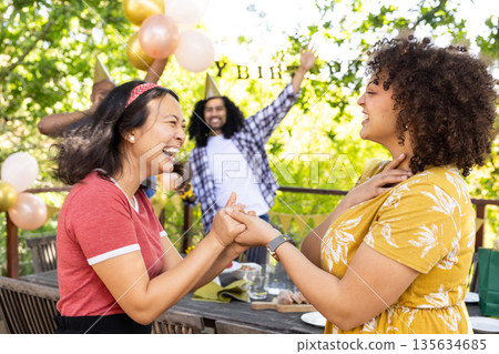 Celebrating birthday outdoors, friends laughing with festive decorations around them 135634685
